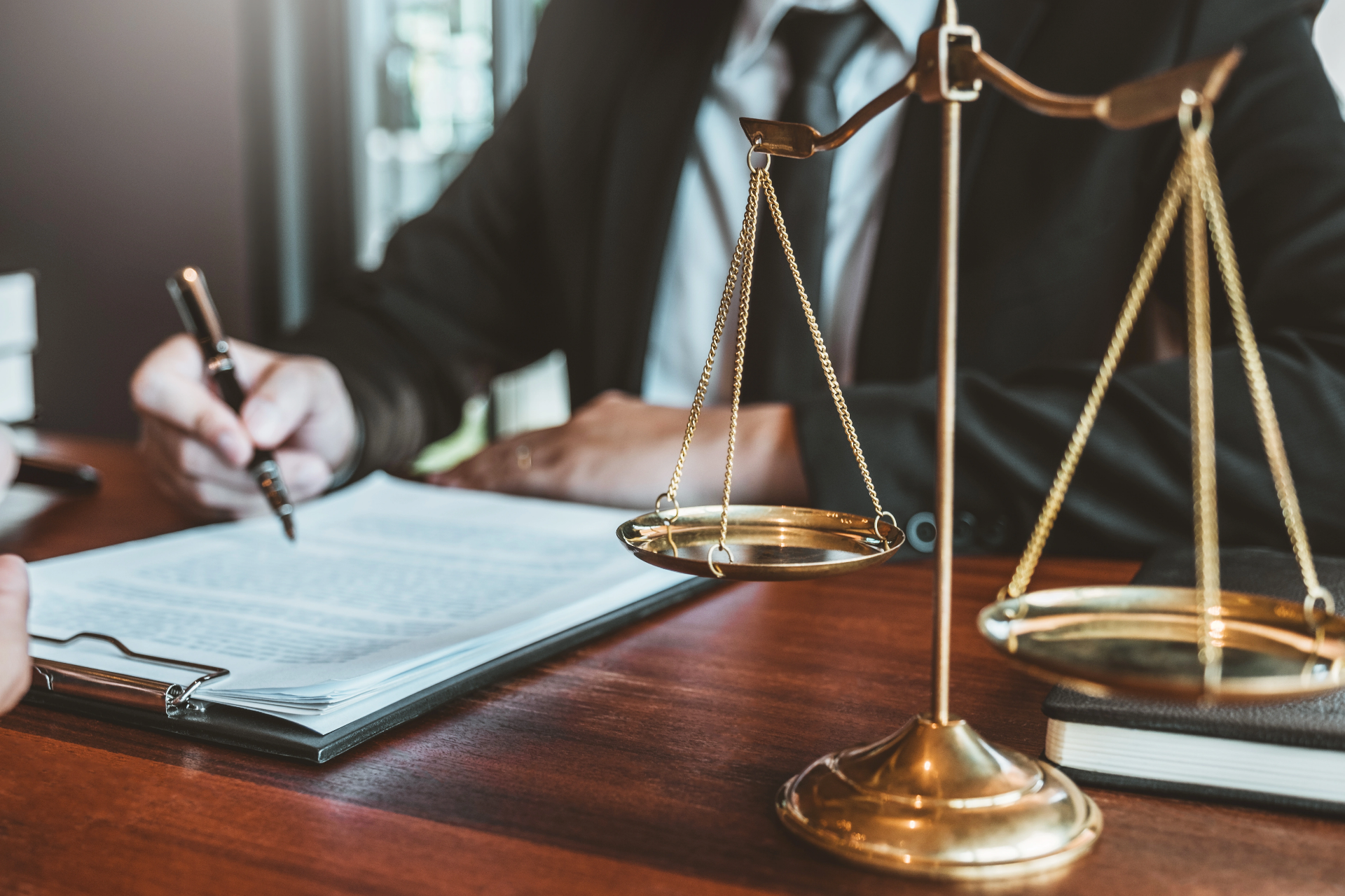 Attorney reviewing legal documents with brass scales of justice